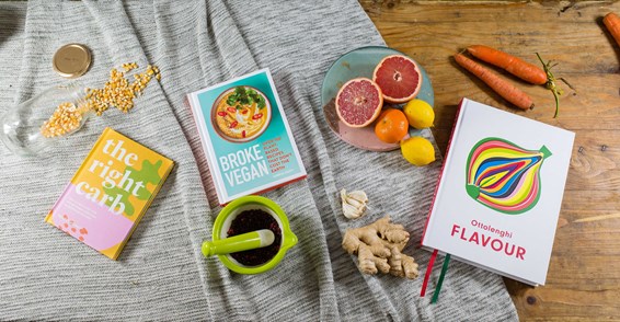 Food books on a table surrounded by food items